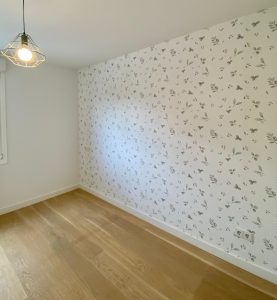 Habitación con papel pintado floral en tonos grises, ambiente sereno y elegante