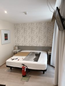 Habitación de hotel con papel pintado tropical en tonos beige, gris y marrón