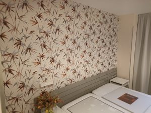 Papel pintado con patrón de hojas en tonos suaves en habitación del Hotel Welcome Gros